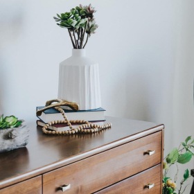 a dresser with a vase of plants on top