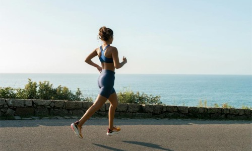 a woman running on a road by the water
