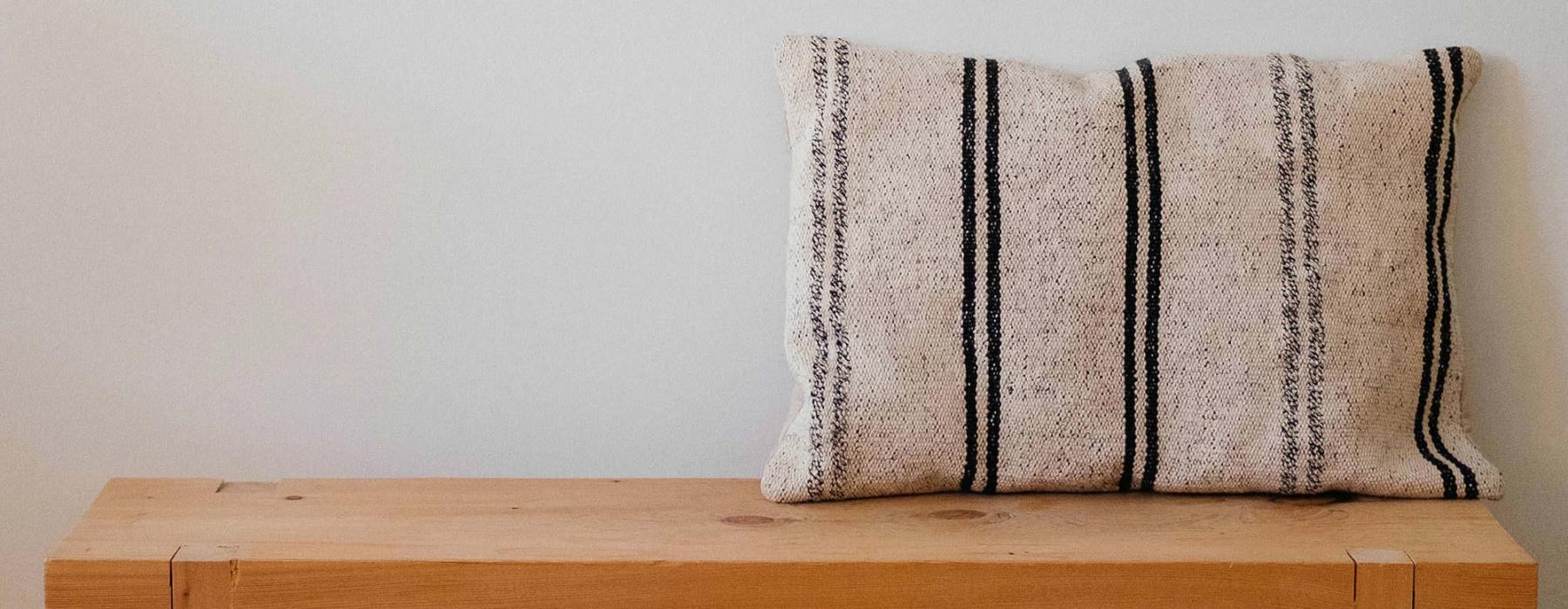 a wooden bench with a striped pillow on it