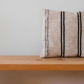 a wooden bench with a striped pillow on it